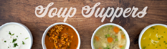 looking down on a wooden table with four bowls with different kinds of soup