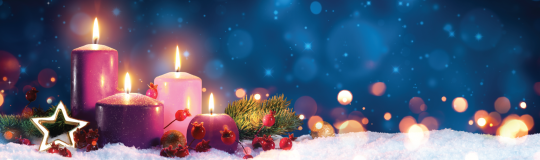 lit purple candles sitting on snow against a blue background with blurred Christmas lights.